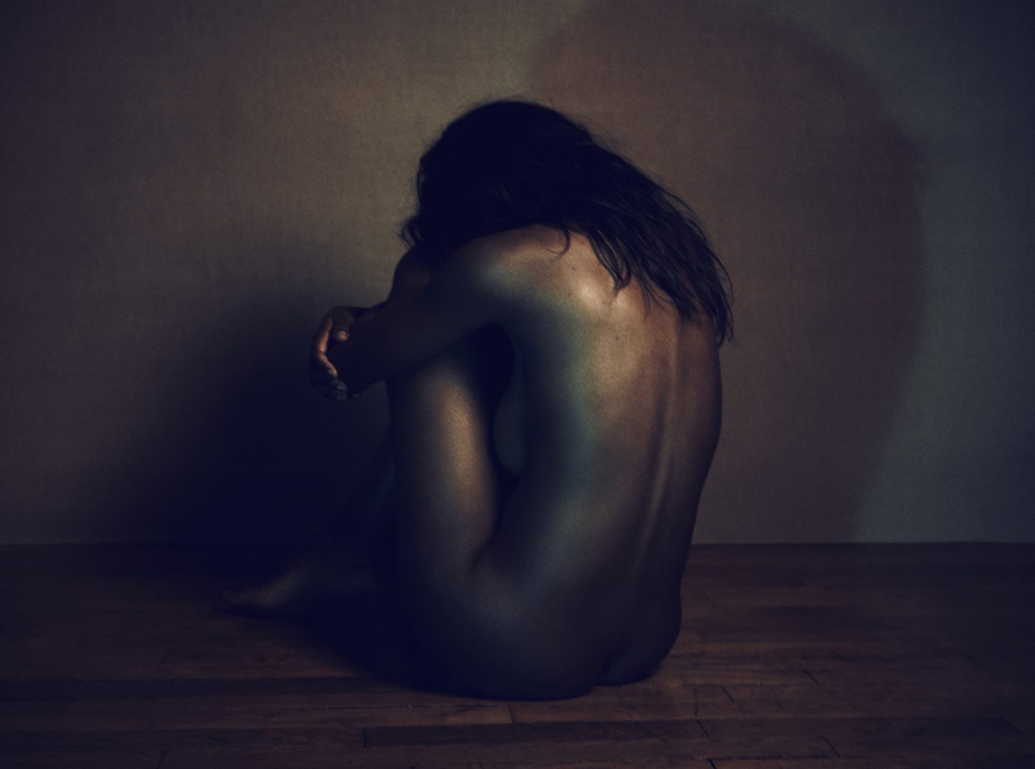 Naked girl with mask sitting on floor by Stefan Rappo