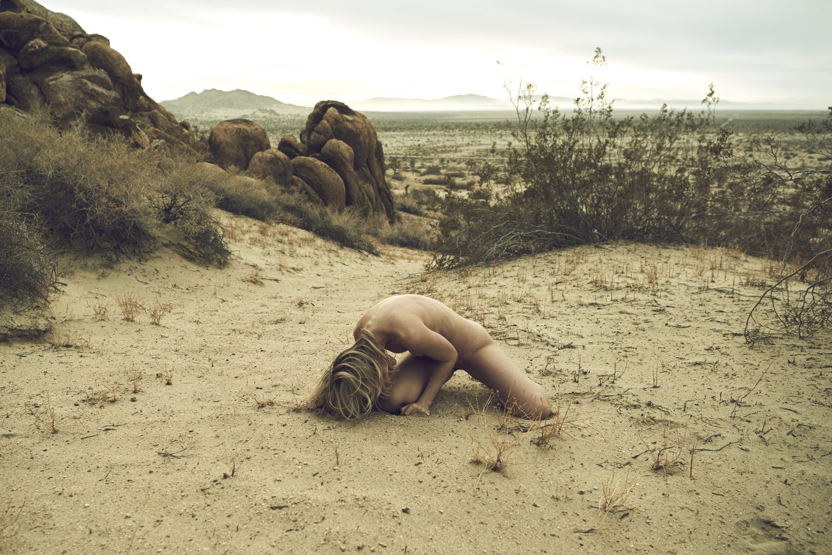 Naked girl on the floor in the desert by Stefan Rappo