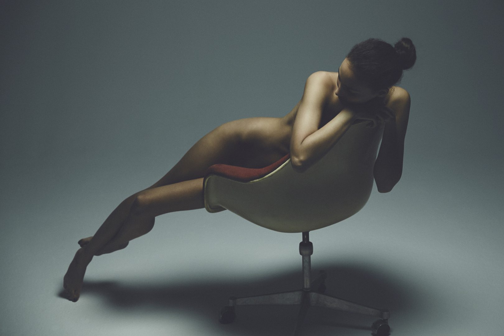 Girl sitting naked on chair by Stefan Rappo