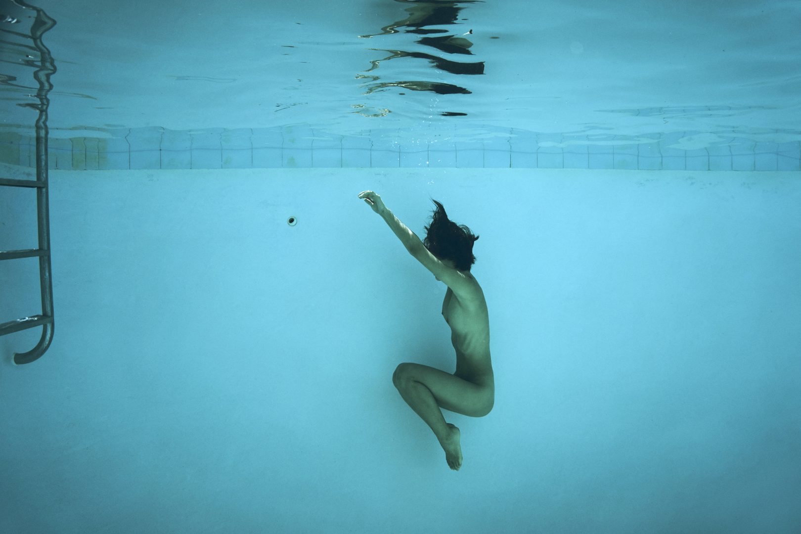 Naked girl diving in swimming pool by Stefan Rappo