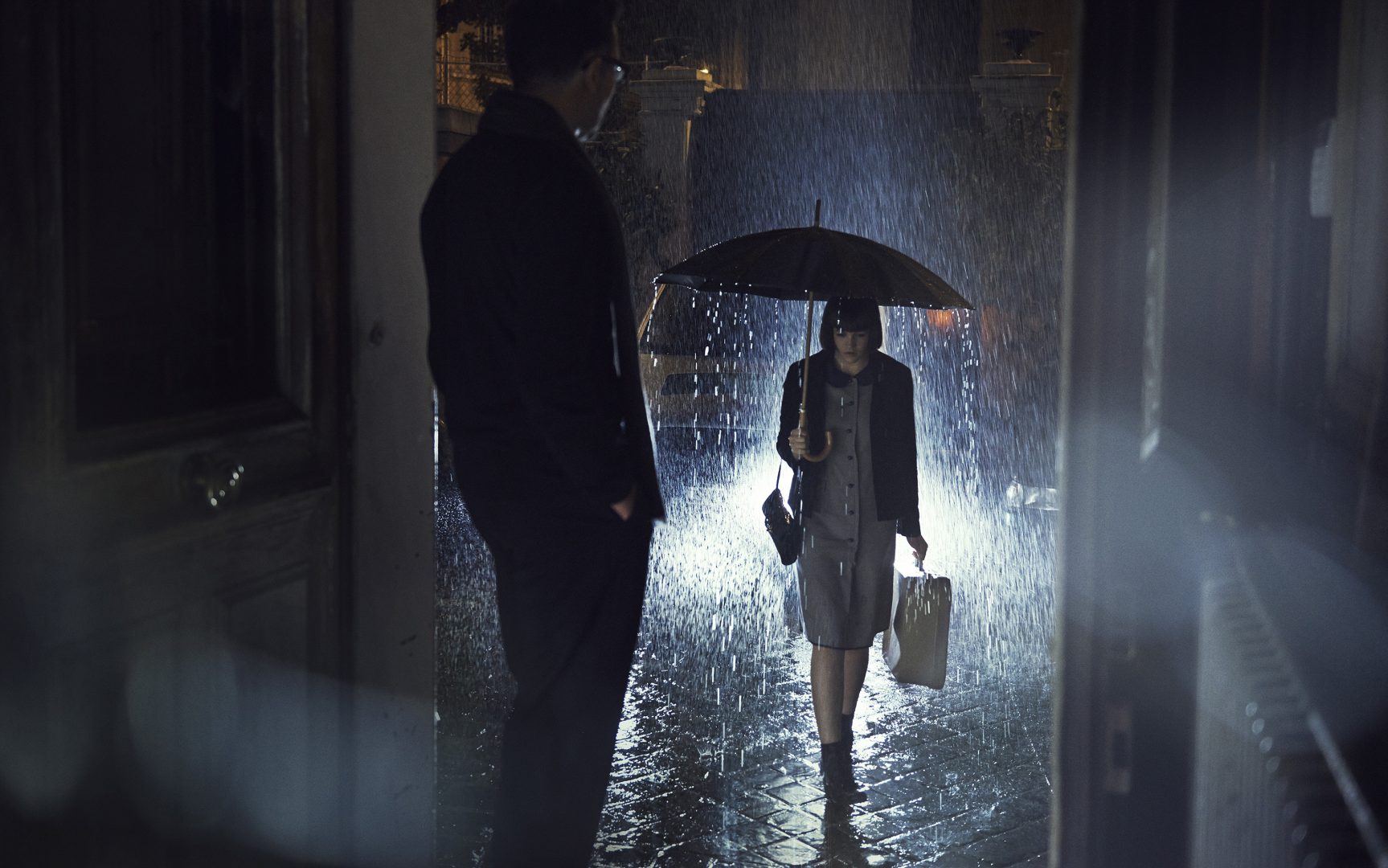 Girl walking to house under rain, man is waiting at her at the door by Stefan Rappo