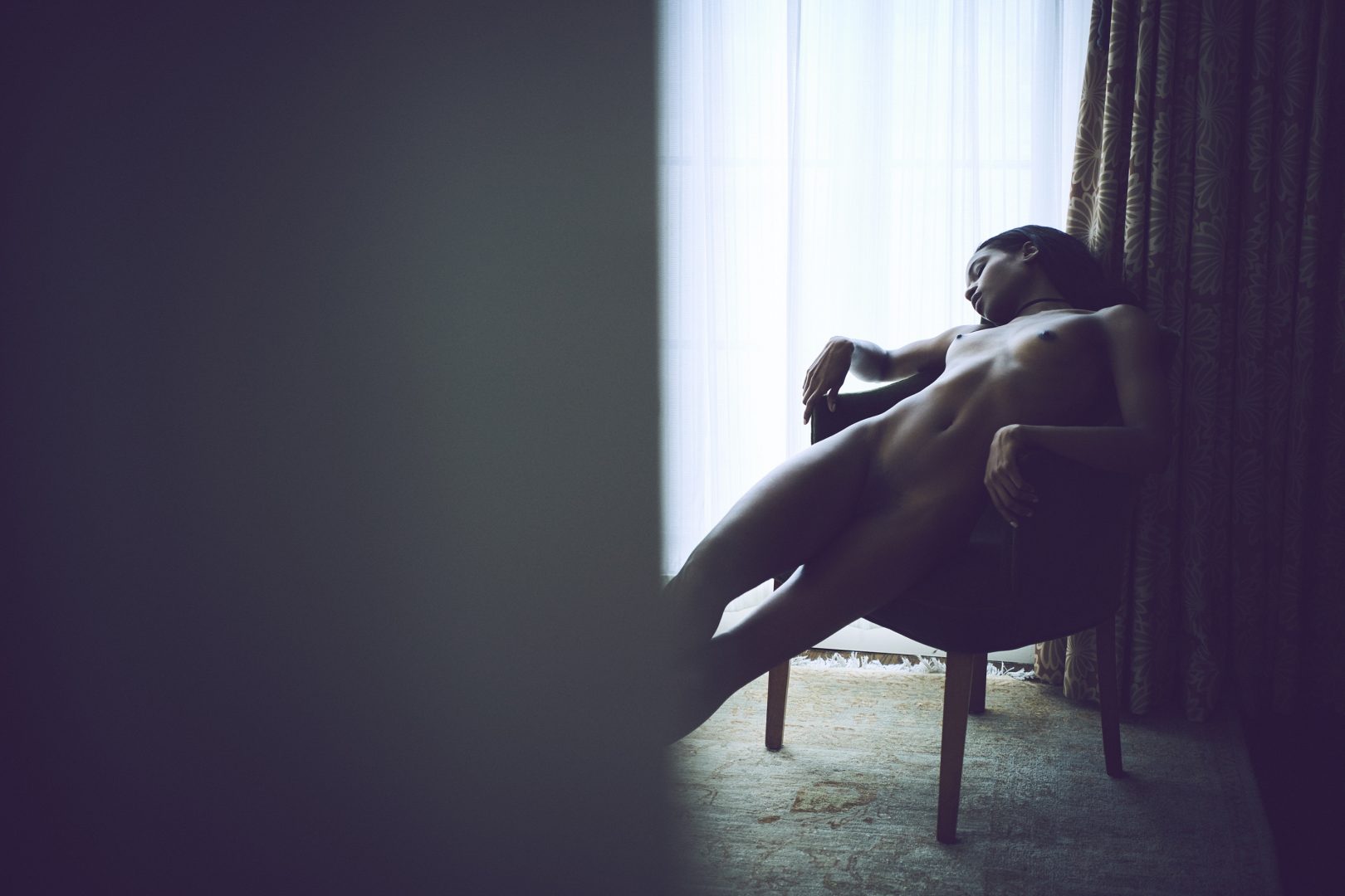 Naked black girl sitting in chair in hotel room by Stefan Rappo