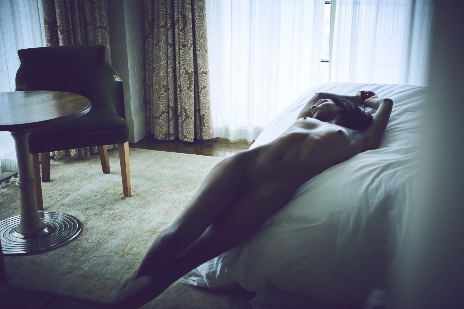 Naked black girl lying on bed in hotel room by Stefan Rappo