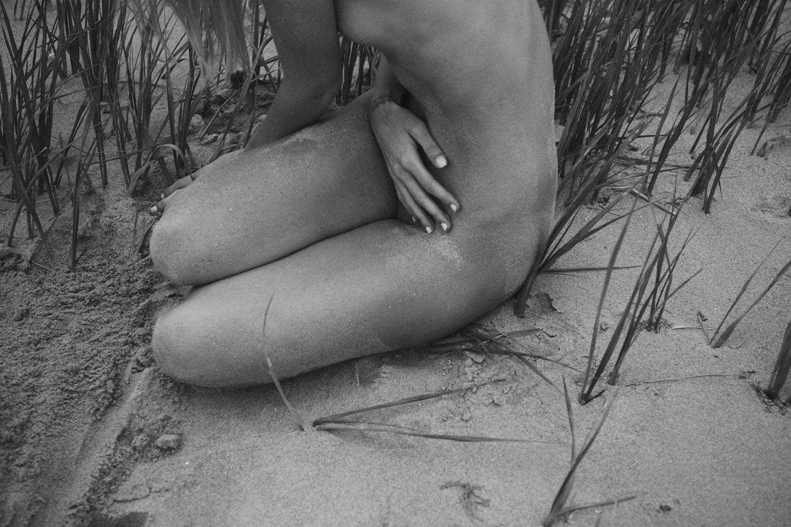 Naked girl sitting on beach by Stefan Rappo