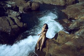Thumbnail naked girl sitting on rock close to river by stefan rappo