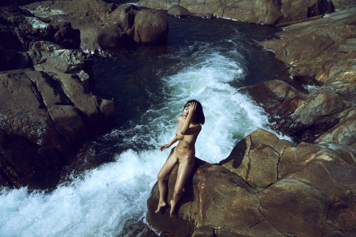naked girl sitting on rock close to river by stefan rappo