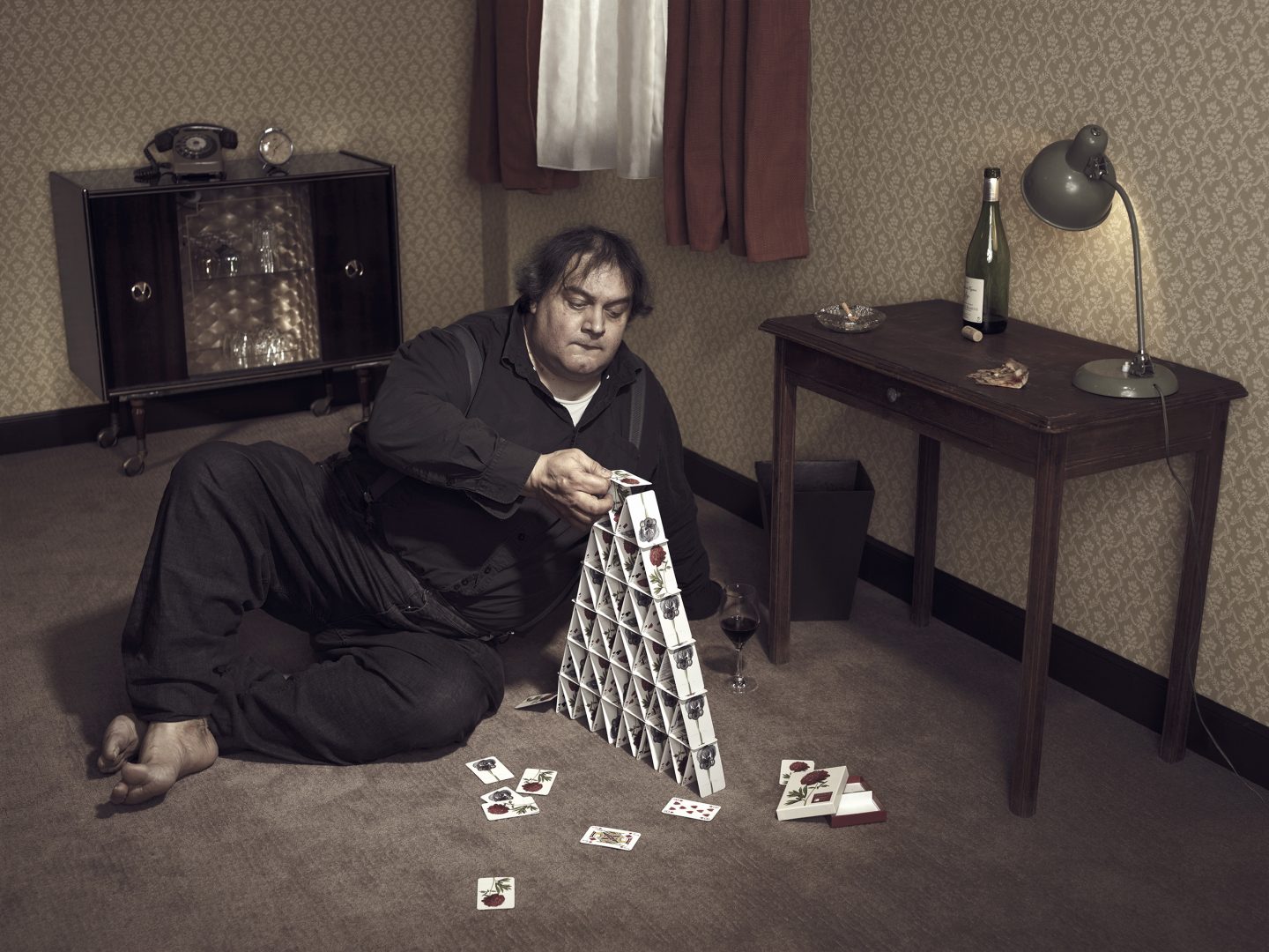 Man on floor is building a card house in room 42 by Stefan Rappo