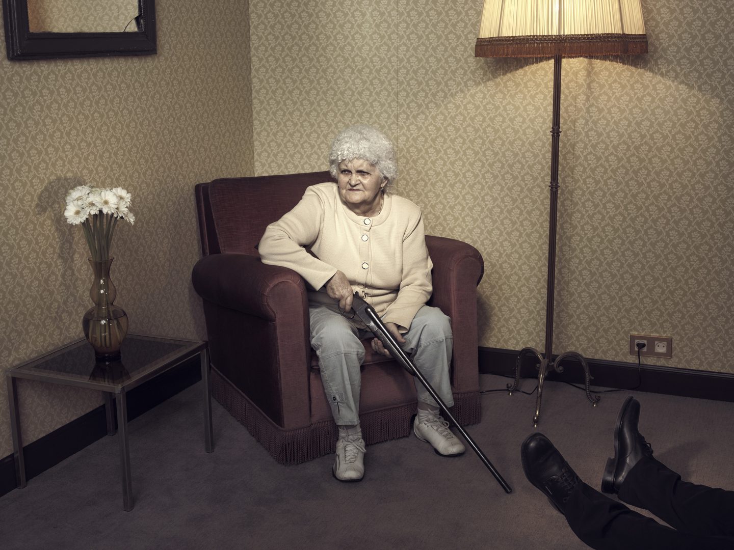 Old lady sitting in chair with gun in room 42 by Stefan Rappo